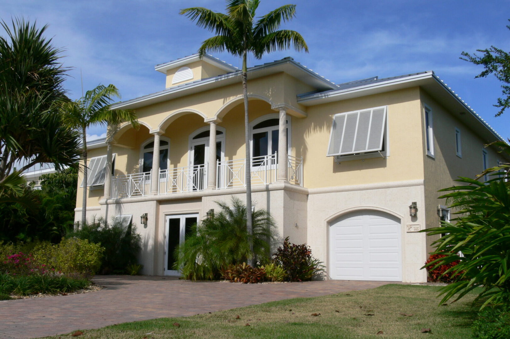 A large yellow house with palm trees in front of it.