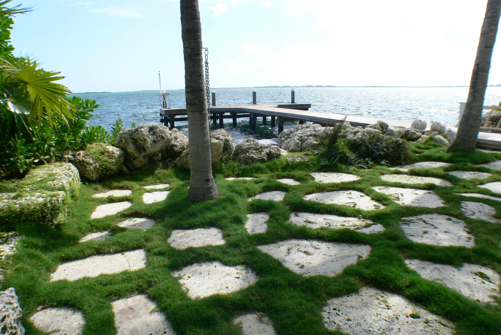 A walkway with grass and rocks next to the water.