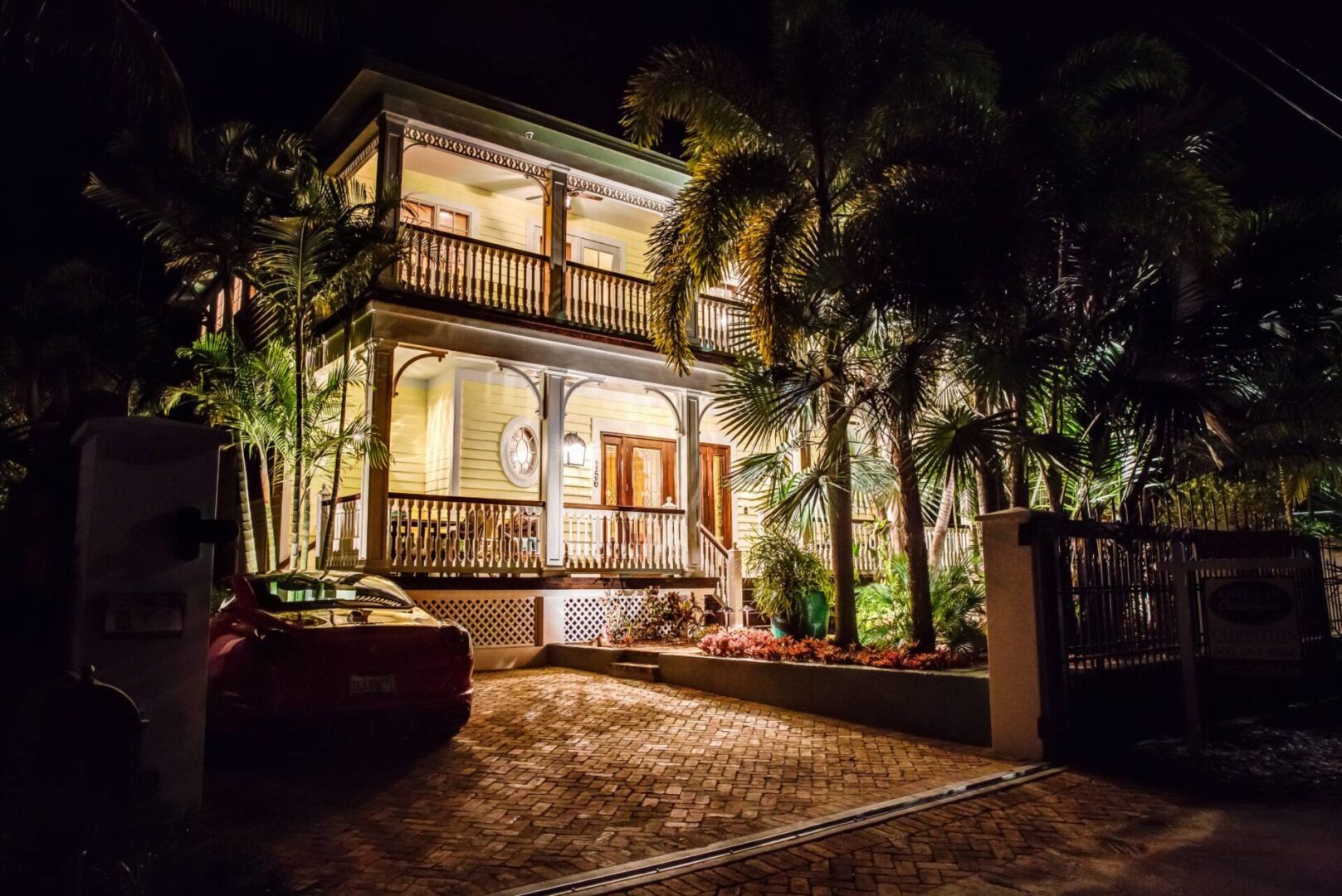A night time photo of a house with palm trees.